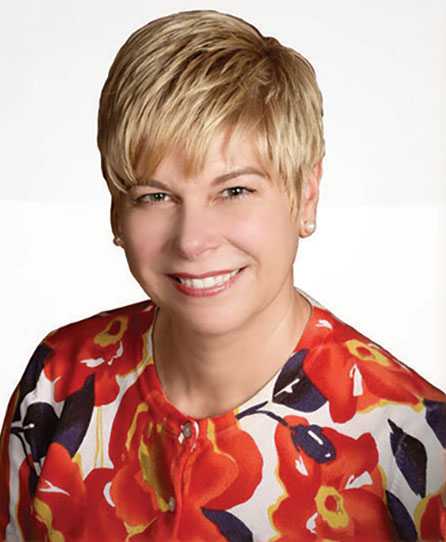 Portrait of Michele Corley in a red floral blouse.